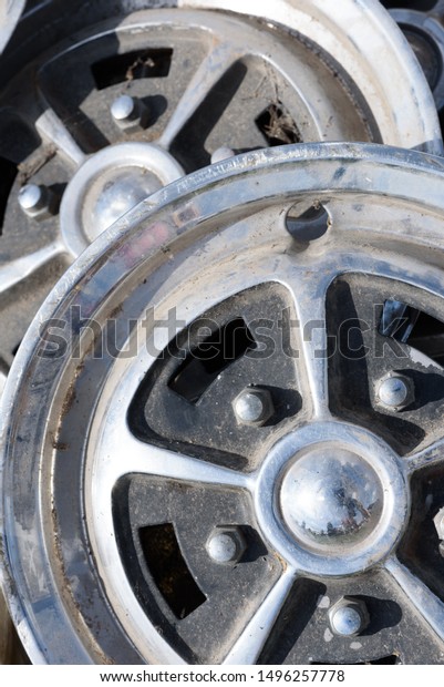 Closeup of tow car wheel\
trims in alloy metal silver with dirt and grime showing their used\
condition