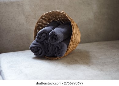 Close-up of a towel stack put inside of a wicker basket tilt sits on a sofa