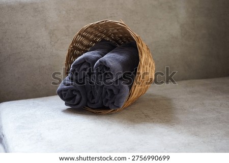Close-up of a towel stack put inside of a wicker basket tilt sits on a sofa