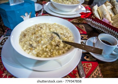 Closeup of traditional Armenian dish harisa - oatmeal with meat. Breakfast in the cafe: porridge, coffee and bread on the table