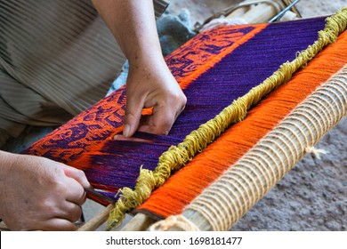Close-up of traditional Aymara red and blue bird patterned weaving in the making on an old fashioned wooden loom
