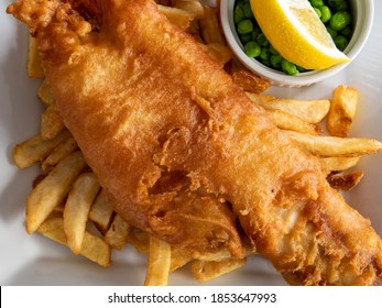 Closeup Of Traditional British Pub Fare, A Crispy Battered Haddock Filet With French Fried Chips And Green Peas