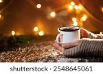 Close-up of traditional Christmas mulled wine with spices. steam. Female hands with mulled wine at the Christmas market or fair.