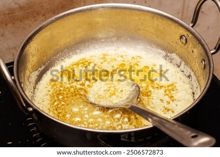 Close-up of a traditional process of making ghee at home from fresh cow milk, showcasing the rich, golden texture of pure clarified butter.