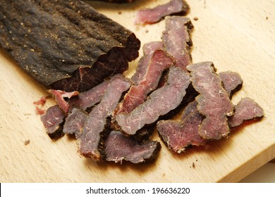 A closeup of traditional south african biltong on a wooden chopping board
