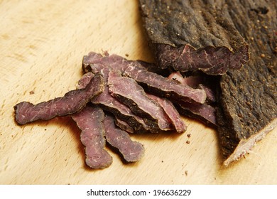 A closeup of traditional south african biltong on a wooden chopping board