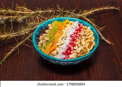 Closeup Of Traditional Turkish Dessert Asure Or Ashura (aka Noah Pudding) In Traditional Green Bowl With Wooden Background. 