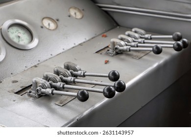 Close-up of a train driver's control panel with multiple levers and analog gauges inside the locomotive cab. The industrial design emphasizes the mechanical and technical aspect of railway transportat
