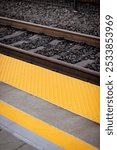 Closeup of train tracks with a safety line with yellow bump texture line on a passenger platform at an empty train station, no people, California US