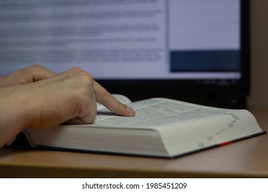 Closeup of a translator working with CAT (Computer-Assisted Translation) tool and dictionary.
