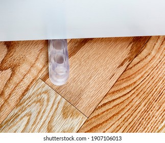 Closeup Of A Translucent Rubber Home Door Stopper Or Slider On Red Oak Floor 