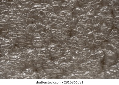 Closeup transparent bubble wrap texture shimmering under soft neutral lighting, highdensity cushioning with glossy reflections and irregular crinkled pockets. Macro abstract
