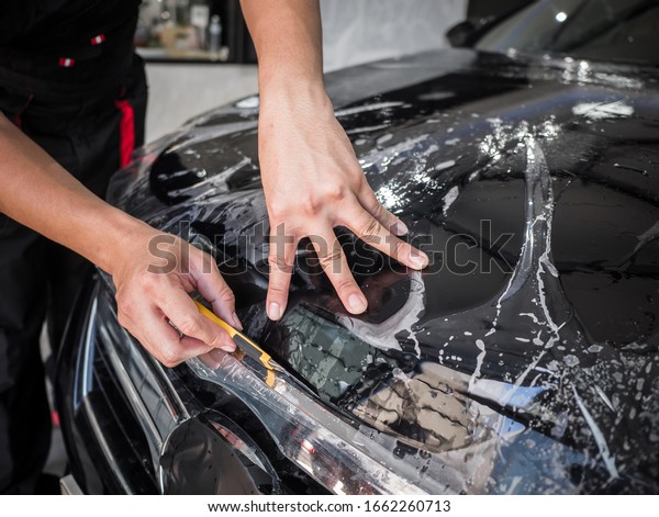 Closeup transparent film, car paint protection.\
Hands installs car paint protection film. Install car paint\
protection film. Car wrap\
concept.