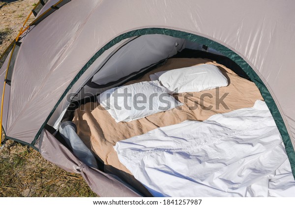 Close-up travel with\
tourist tent with comforts in the form of pillows and blankets in a\
camping by the sea