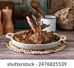 A closeup of a tray of deliciously cooked lamb chops with herbs on a wooden surface