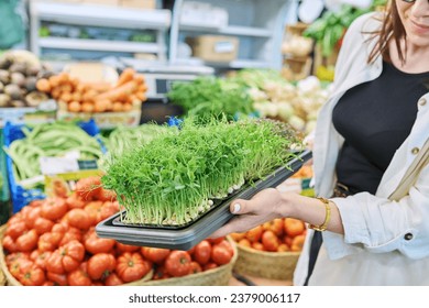 Close-up of trays with various microgreens in hands of woman at farmer's market - Powered by Shutterstock