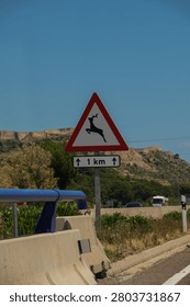 Close-up of a triangular warning traffic sign for wild animals crossing with an ancient fortress on a hill background in Spain.