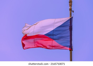 Close-up of the tricolor national flag of the Czech Republic on a bronze flagpole with a lion's head in a golden crown against a clear sky on a sunny day in Prague, Czech symbols