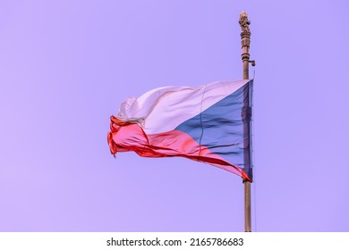 Close-up of the tricolor national flag of the Czech Republic on a bronze flagpole with a lion's head in a golden crown against a clear sky on a sunny day in Prague, Czech symbols