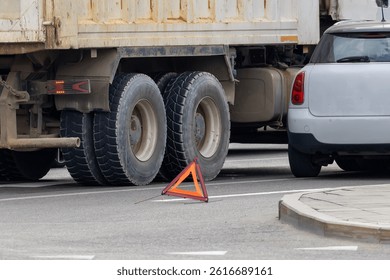 Close-up of a truck and car colliding on a city street with a warning triangle in the foreground. Minor accident. Road accident between a truck and a car on a city street