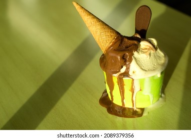 Close-up Of A Tub Of Melting Ice Cream On A Green Table Background On A Sunny Day.