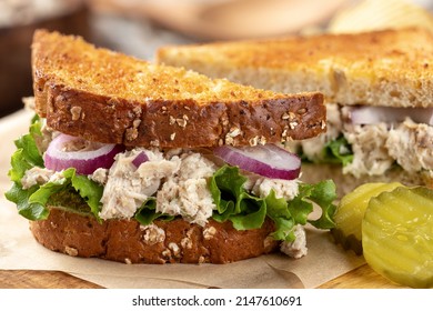 Closeup Of Tuna Salad Sandwich With Lettuce And Onion On Toasted Whole Grain Bread Cut In Half On A Cutting Board