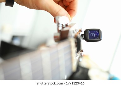 Close-up Of Tuner And Hands Of Musician Tuning String Instrument. Man Using Special Device For Electric Or Acoustic Guitar. Performer Preparing For Performance