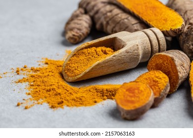 Close-up Turmeric curcumin powder in wooden spoon and fresh curcuma or curcumin on concrete background. Spice, natural coloring, alternative medicine. Long banner format. top view.