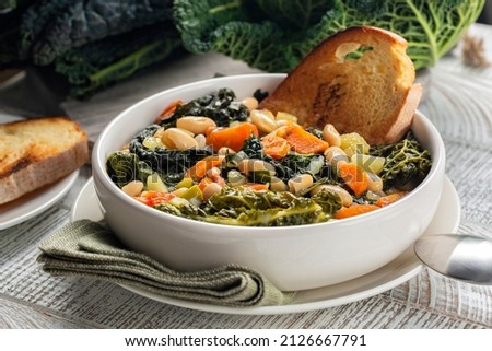 Close-up of Tuscan vegetarian bread Soup made with toasted bread and vegetables. Ribollita. Cannellini beans, lacinato kale, cabbage verza, carrot, celery, potatoes, and onion. Itralian food. 