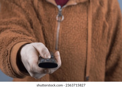 a close-up of the TV remote in the woman's hand, the TV remote is directed at us. TV control - Shutterstock ID 2363715827