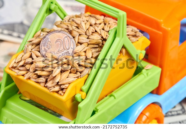 Close-up of twenty\
cent euro coin in the body of a toy truck that transports grain on\
a background of dollar\
bills