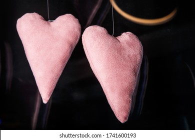 Closeup Two Big Soft Pink Heart Shaped Handmade Toys Hanging On White Fishing Line Against Dark Glass Background