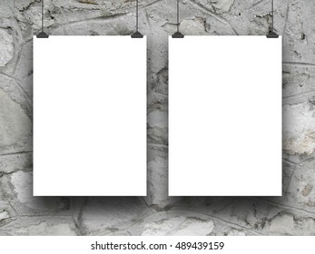 Close-up of two blank frames hanged by clips against gray stone wall background