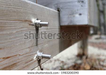 A close-up of two bolts with bolted washers and nuts sticking out of the board