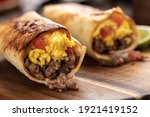 Closeup of two breakfast burritos with scrambled egg, sausage and tomato in a tortilla wrap