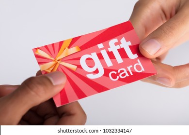 Close-up Of Two Businesspeople Hand Holding Red Gift Card