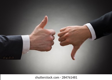 Close-up Of Two Businesspeople Hands Showing Thumb Up And Thumb Down Sign