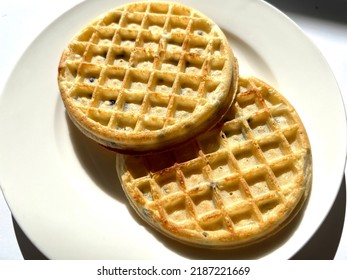 Closeup of two chocolate chip frozen waffles on a white plate against a white background. Plain, no toppings in high contrast light. - Shutterstock ID 2187221669