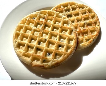 Closeup of two chocolate chip frozen waffles on a white plate against a white background. Plain, no toppings in high contrast light. - Shutterstock ID 2187221679