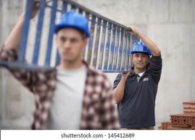 Closeup Of Two Construction Workers Carrying Ladder