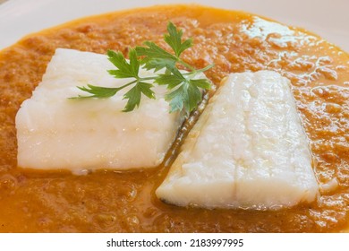 Close-up Of Two Cooked Cod Loins Decorated With A Fresh Sprig Of Parsley In Tomato Sauce. Fish And A Healthy Diet.