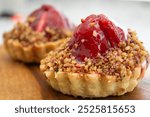 Close-up of two delicious mini tarts topped with red fruit filling and a crunchy nut crust.