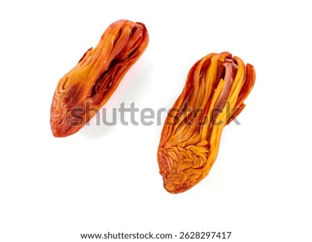 Close-up of two dried Javitri isolated on a white background, showcasing their unique texture and vibrant orange color.