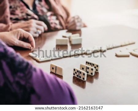 close-up of two elderly people playing dominoes. unrecognizable people. concept of fun and old age. selective blur. detail on the dominoes.