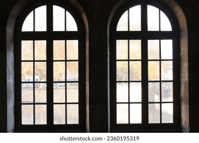 Close-up of two elegant old windows in backlighting, offering a view through the panes to the daytime scene. - Powered by Shutterstock