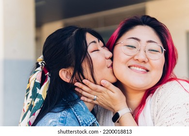 Close-up Of Two Emotional Happy Asian Female Friends Hugging And Kissing, Meeting Again In The City