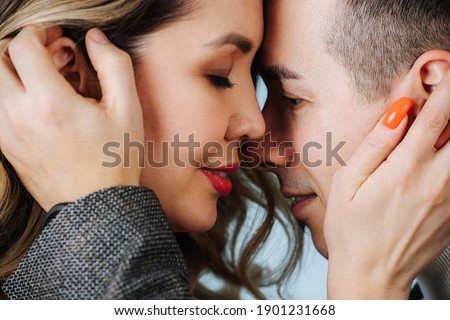 Close-up of the two faces of lovers, touching each other with their hands and noses.