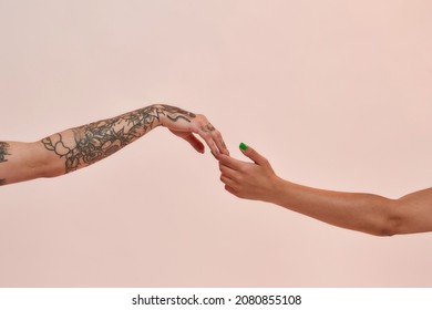 Closeup of two female arms reaching each other hand isolated over light pink background. Lgbtq, youth, love concept - Shutterstock ID 2080855108