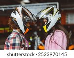 Close-up of two female go-kart racers facing each other, wearing helmets, ready for competition.