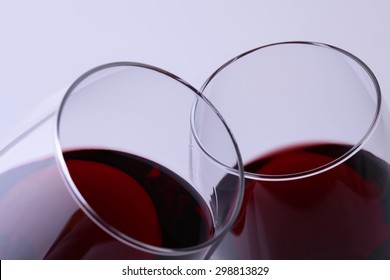 Closeup Of Two Glasses With Red Dessert Grapes Wine Clinking In Toast Standing Close To Each Other With Thin Rims Isolated On Light Grey Background, Horizontal Picture